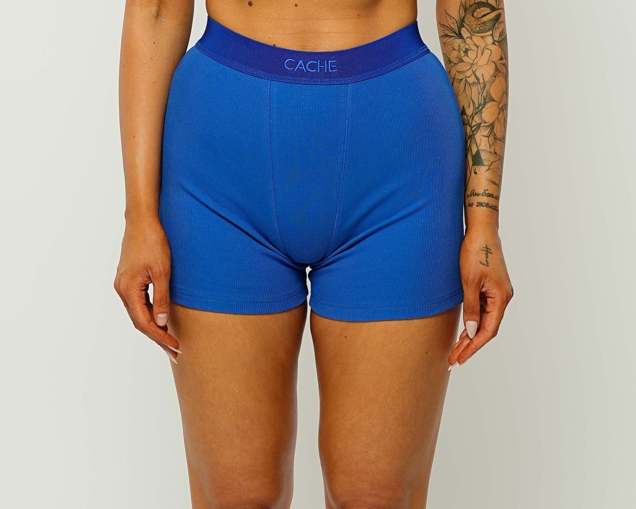 Woman wearing a blue sports bra and shorts set on a white background