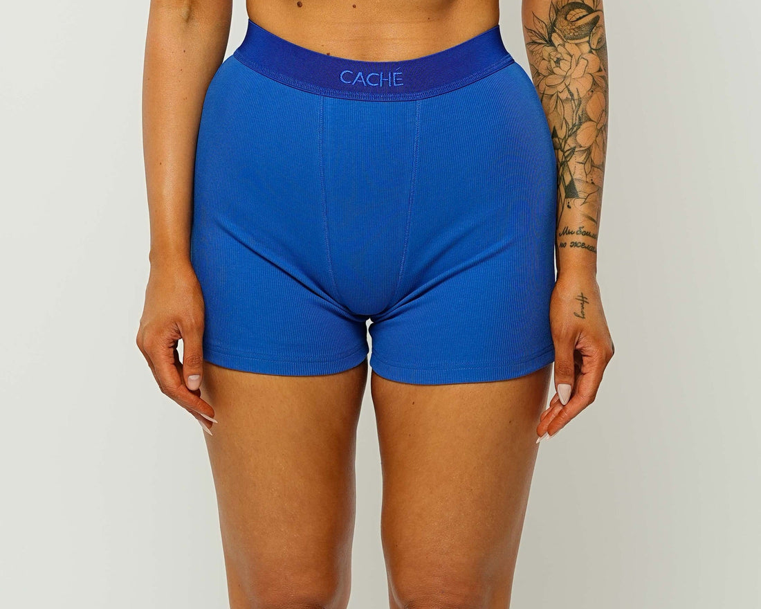 Woman wearing a blue sports bra and shorts set on a white background