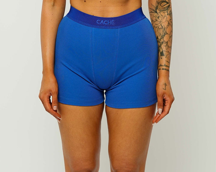 Woman wearing a blue sports bra and shorts set on a white background