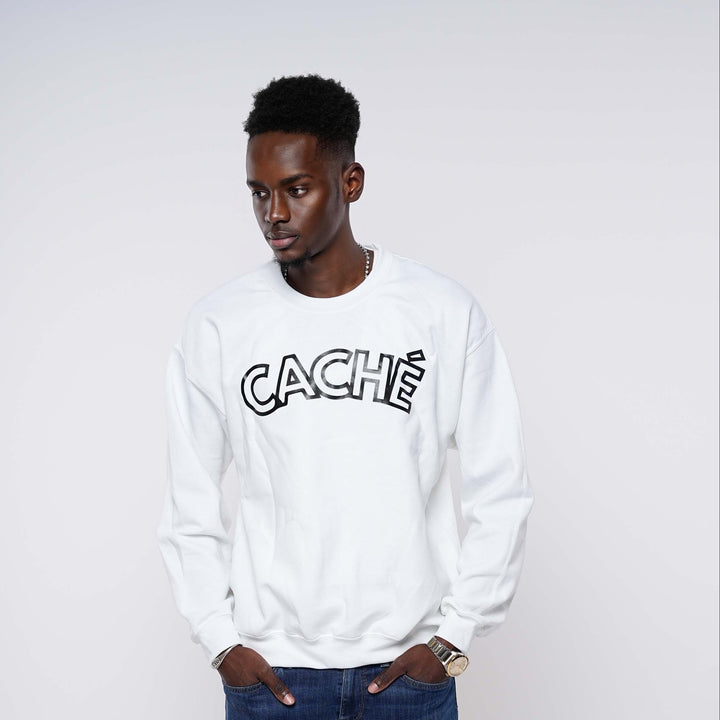 Man wearing a white sweatshirt with 'CACHE' logo and blue jeans on a white background